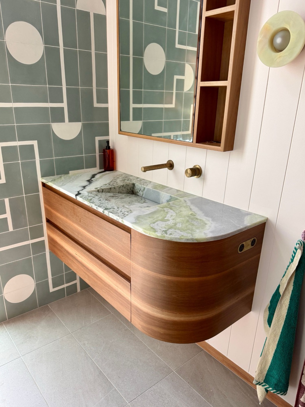 Floating curved timber vanity with a green stone top