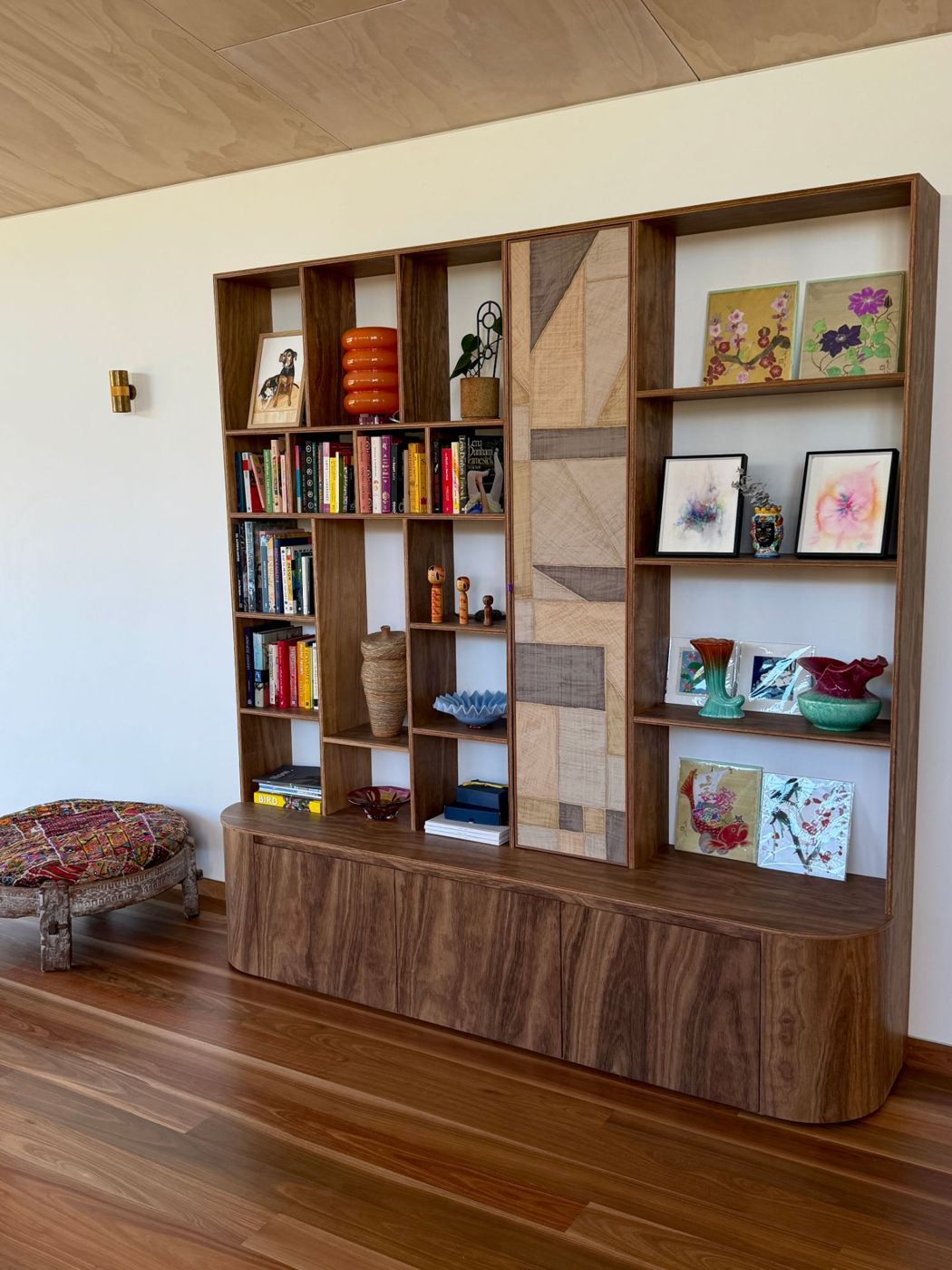 Timber wall unit with open shelving and a patterned centre door, above a curved-end cabinet base